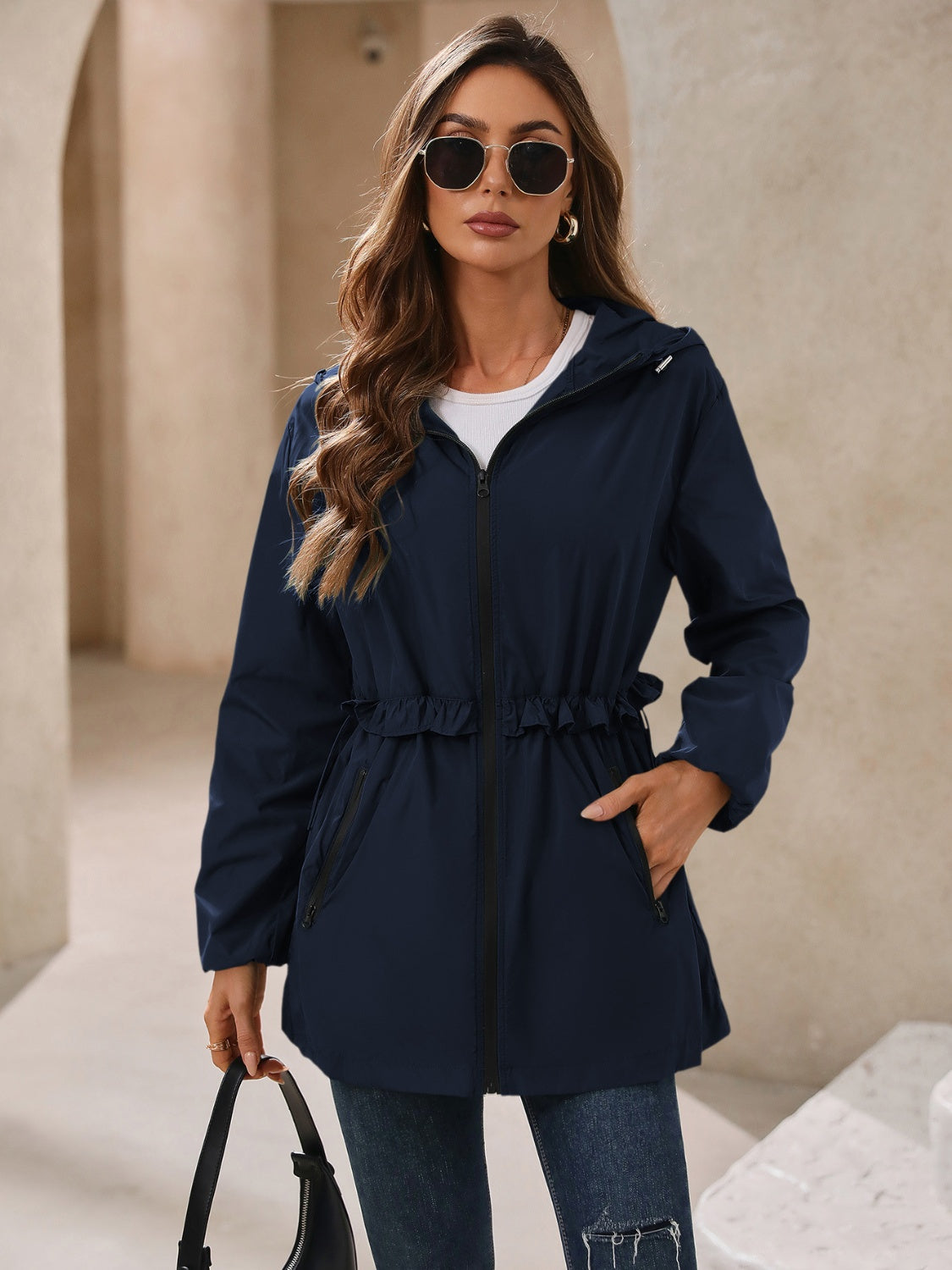 Navy hooded windbreaker jacket with zip front, cinched waist, and drawstring hem
