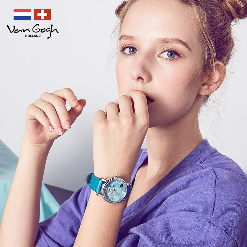 Women's quartz watch on wrist with turquoise band and teal floral dial near face.