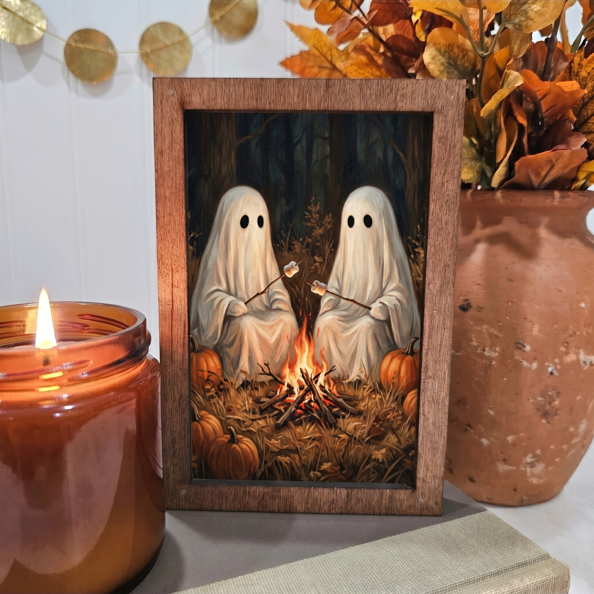 Wood block sign with two white ghosts roasting marshmallows by campfire