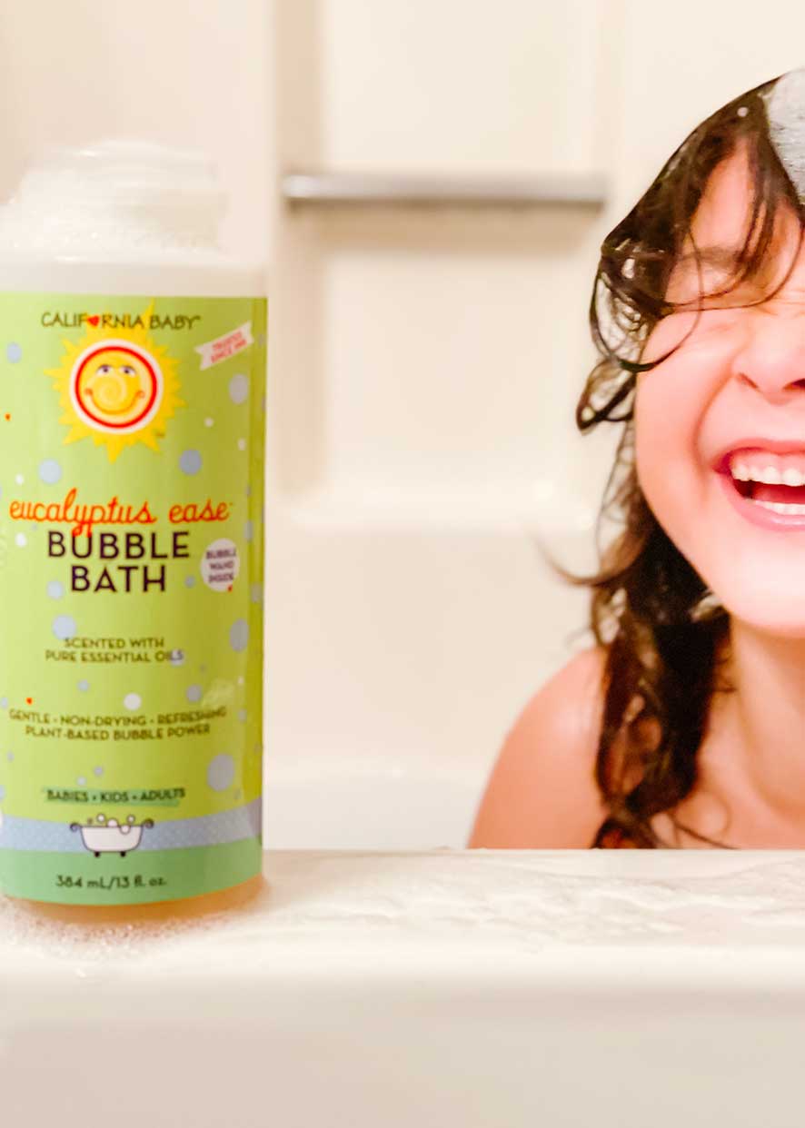 Eucalyptus bubble bath bottle in bath tub with bubbles and smiling person
