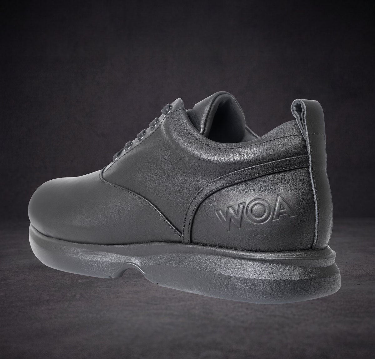 WOA low-top sneaker heel and side view, dark leather with WOA logo