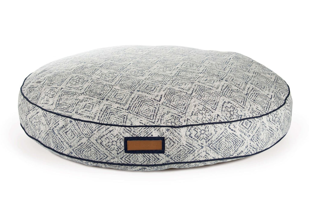 Round pet bed with gray geometric top and dark blue piping; front label tab