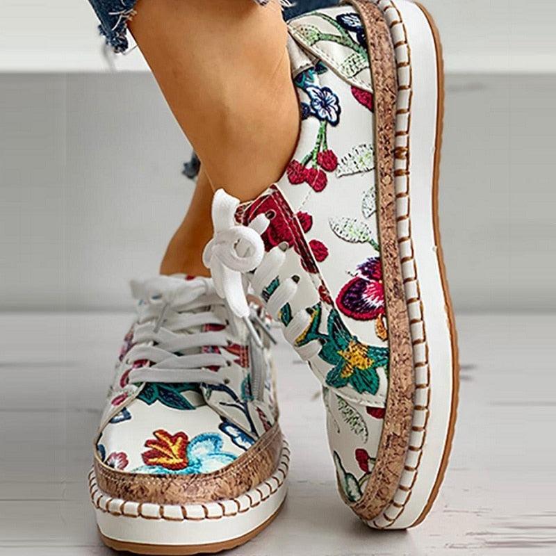 Floral lace-up women’s sneaker close-up, white upper with multicolor leaf and bird print