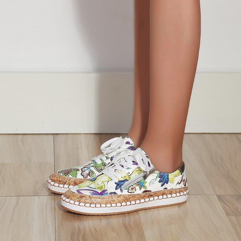 Floral lace-up women’s sneaker on foot, white upper with multicolor butterfly print