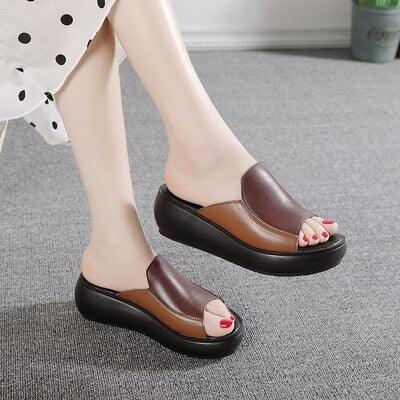Brown and black open-toe platform wedge slip-on slippers worn by model