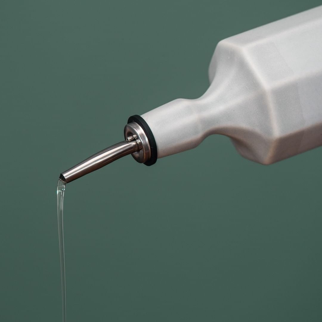 Silk white porcelain olive oil dispenser with metal spout dispensing oil