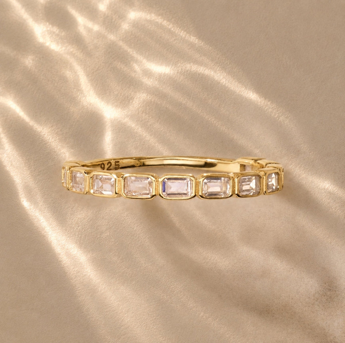 Gold-tone eternity band ring with rectangular clear stones, side view