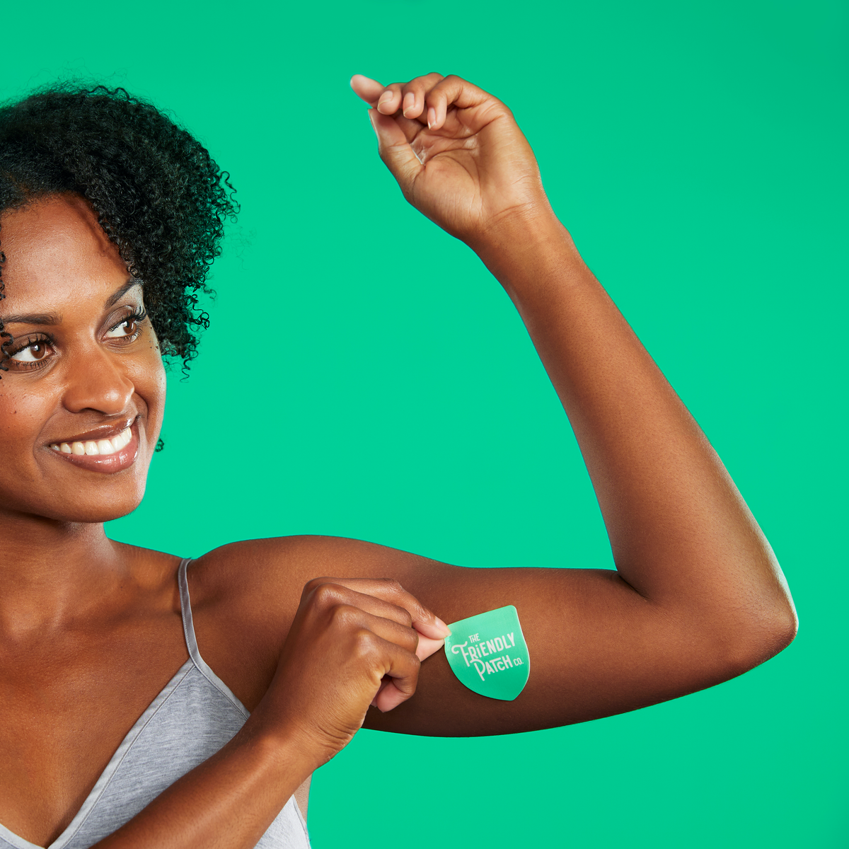 Green vitamin patch applied to upper arm on a smiling woman