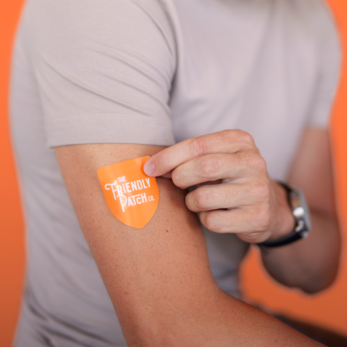 Orange triangle vitamin patch applied to upper arm on a person's skin