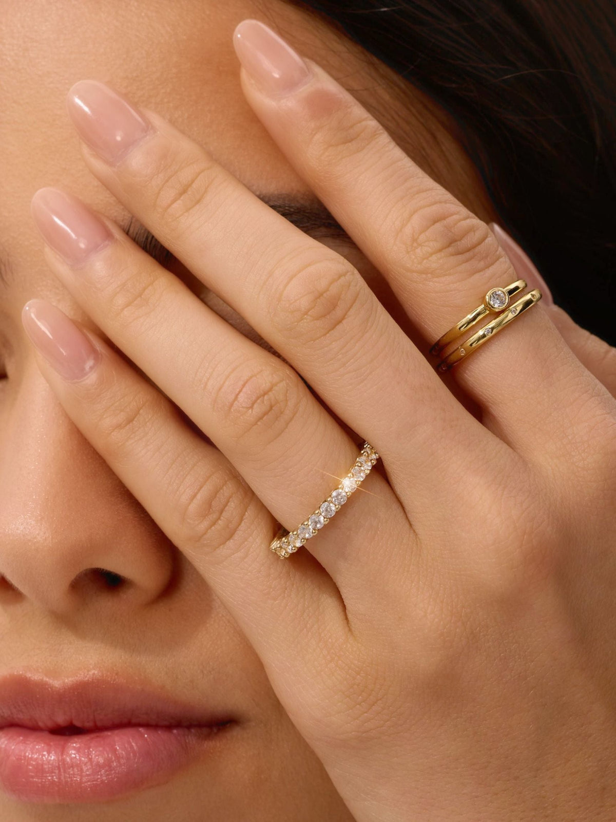 Gold eternity ring with small clear stones on finger