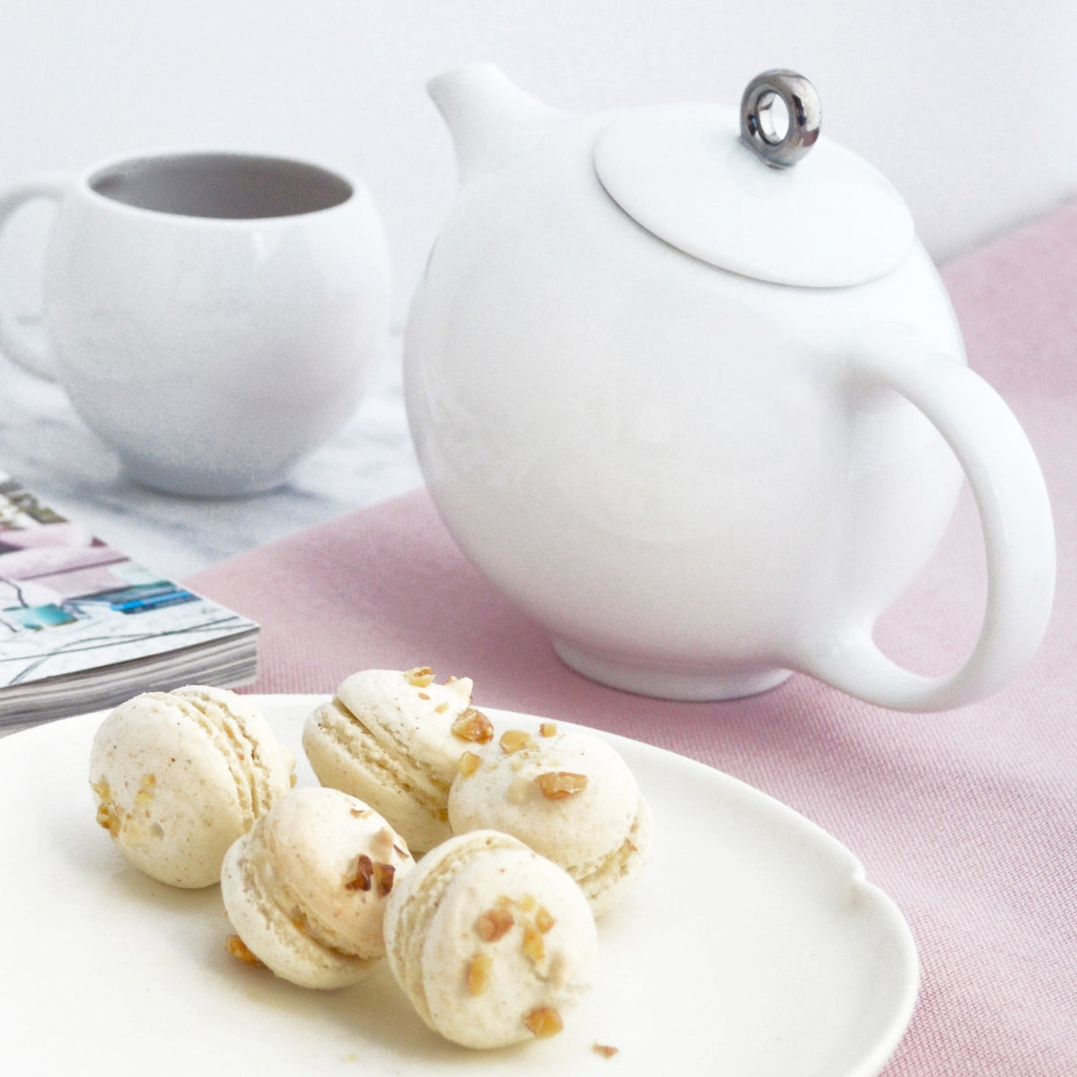 White ceramic teapot with infuser and metal-topped lid on table