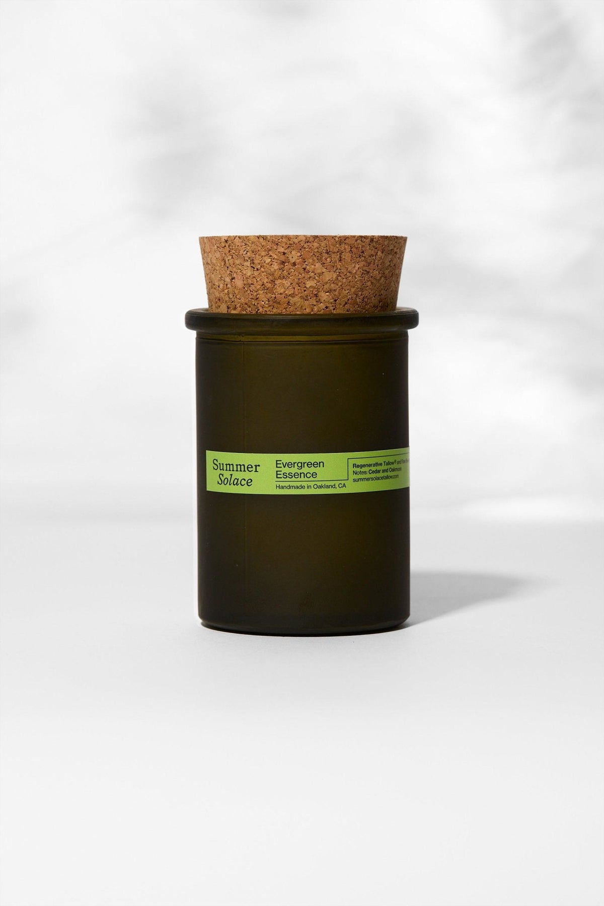 Dark green candle in a glass jar with cork lid and green label