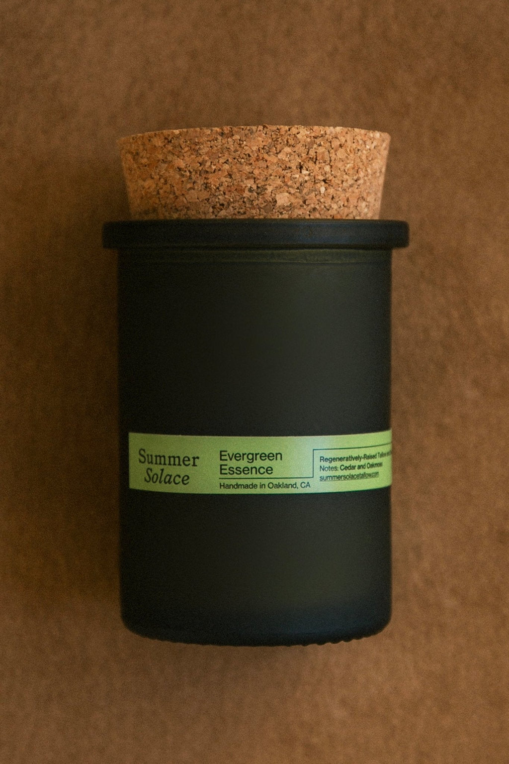 Close-up of dark green candle jar with cork lid and green label