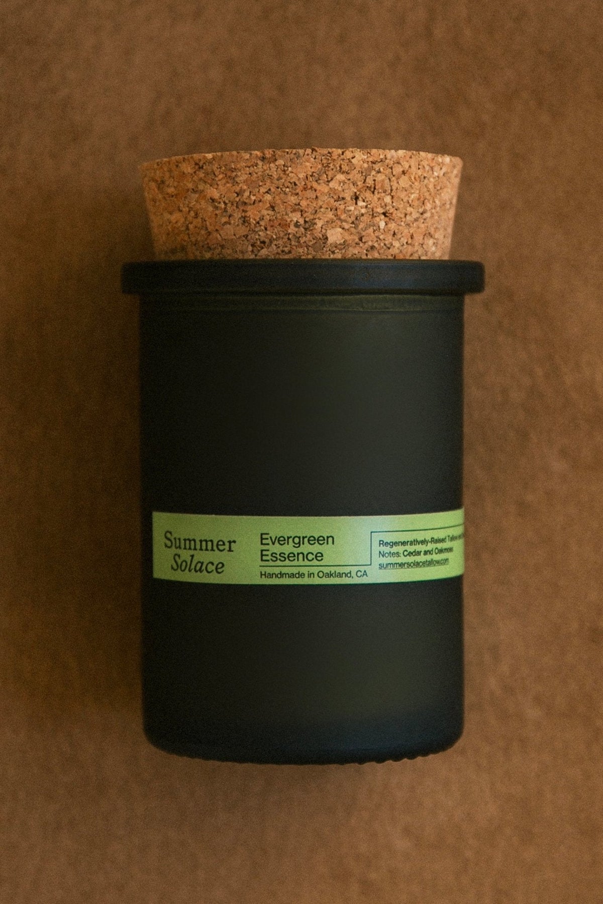 Close-up of dark green candle jar with cork lid and green label