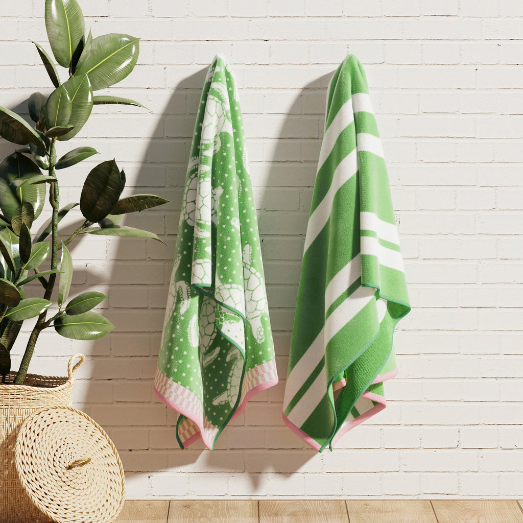 Green cotton velour towels hanging on wall, with striped and sea-turtle designs