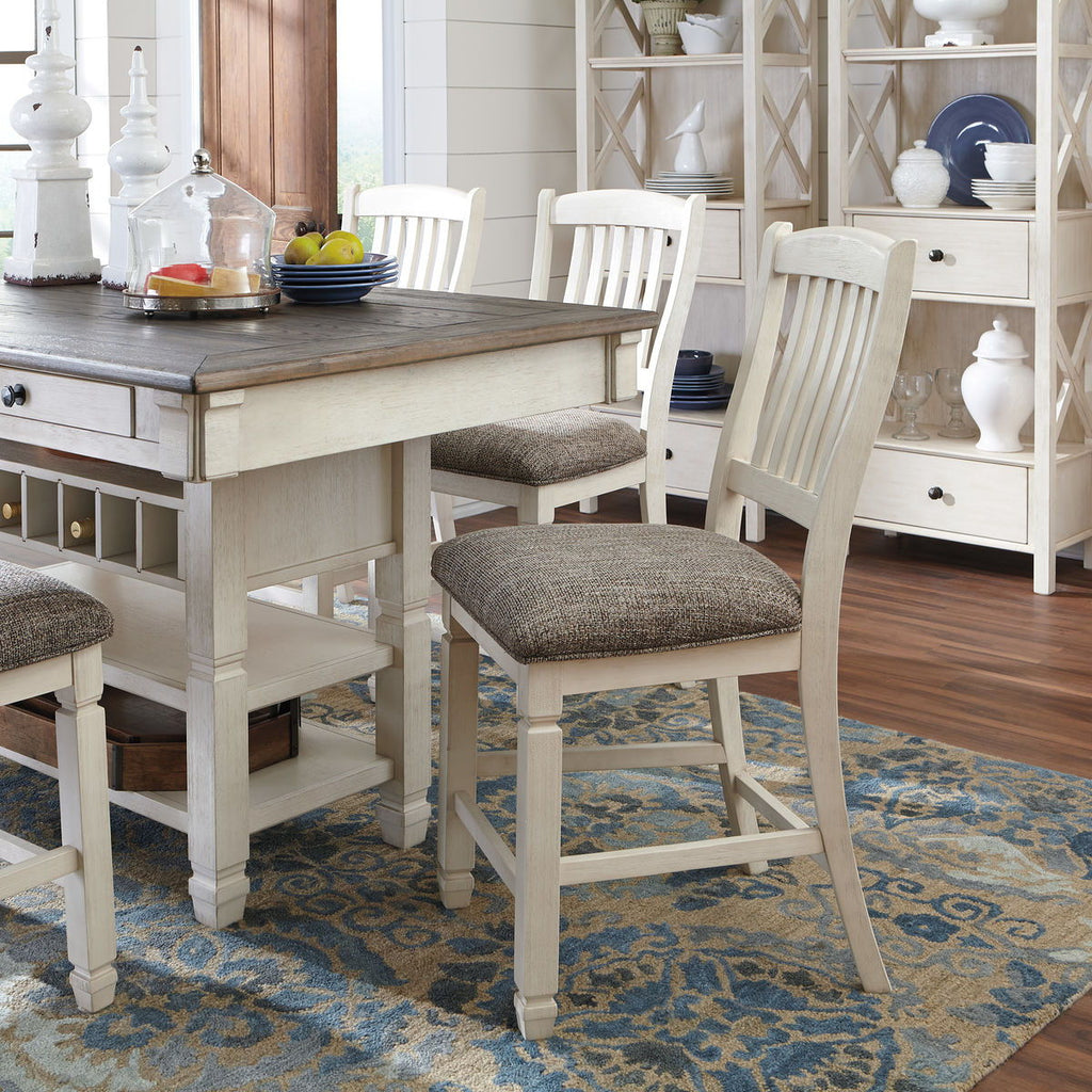 Beige rectangular counter table with gray upholstered stools and ladder-back chairs