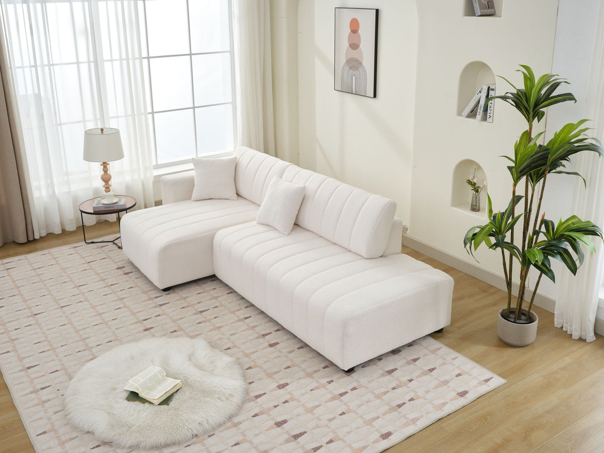 Beige sectional sofa with chaise and armrest detail; long tufted seat cushions.