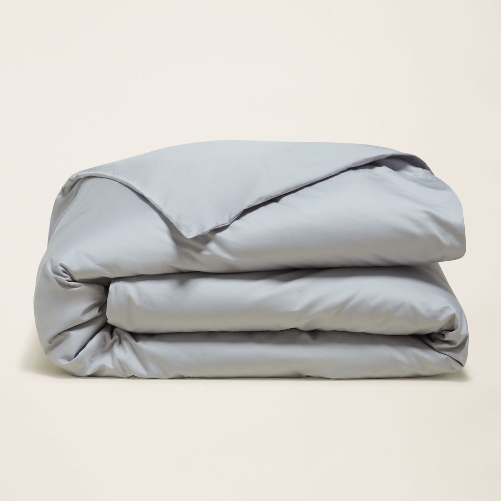 Light blue sateen duvet cover, folded in three layers with satin sheen.