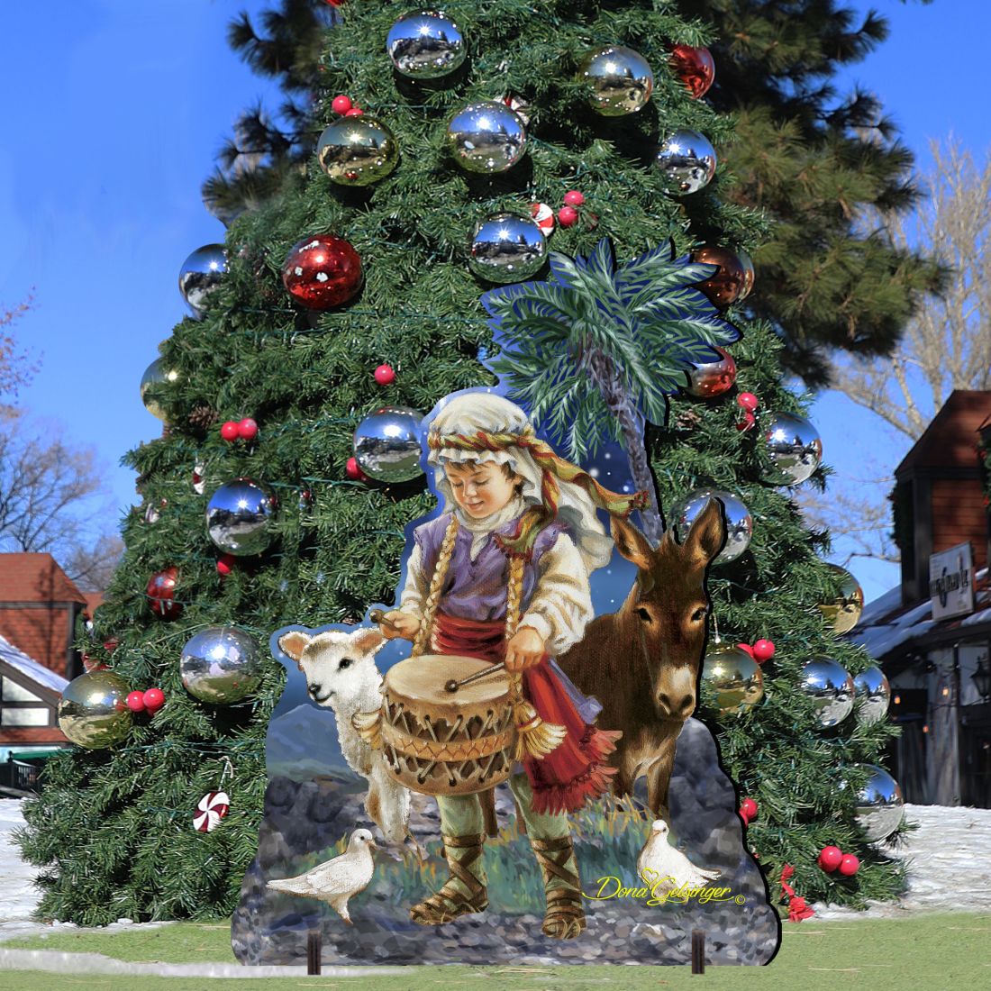 Nativity outdoor decor in front of decorated Christmas tree: drummer boy with drum