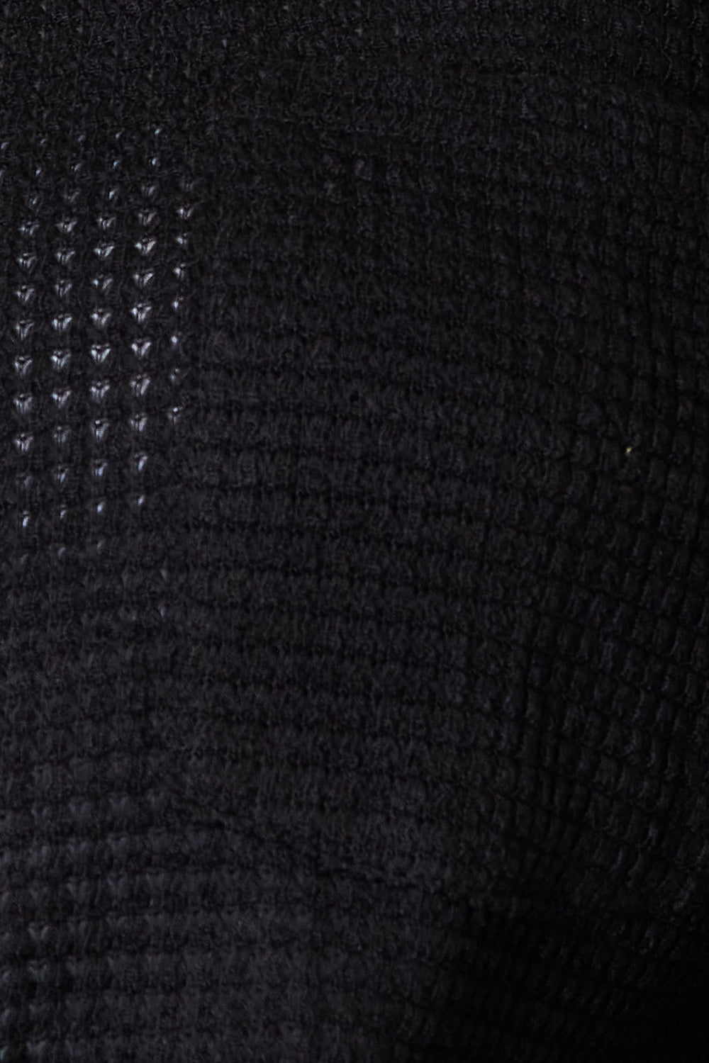 Close-up of black waffle-knit fabric texture with small raised square pattern