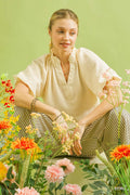 Ecru textured blouse with V-neck, gathered neckline, and scalloped hem