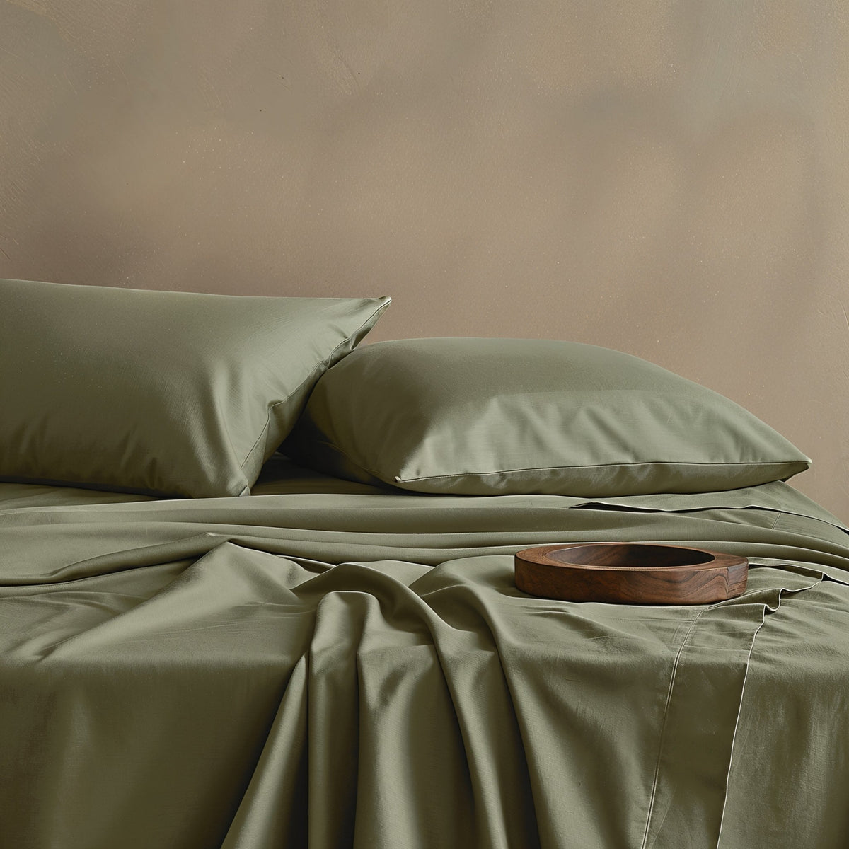 Moss green sateen bedding bundle with folded duvet and pillow shams close-up