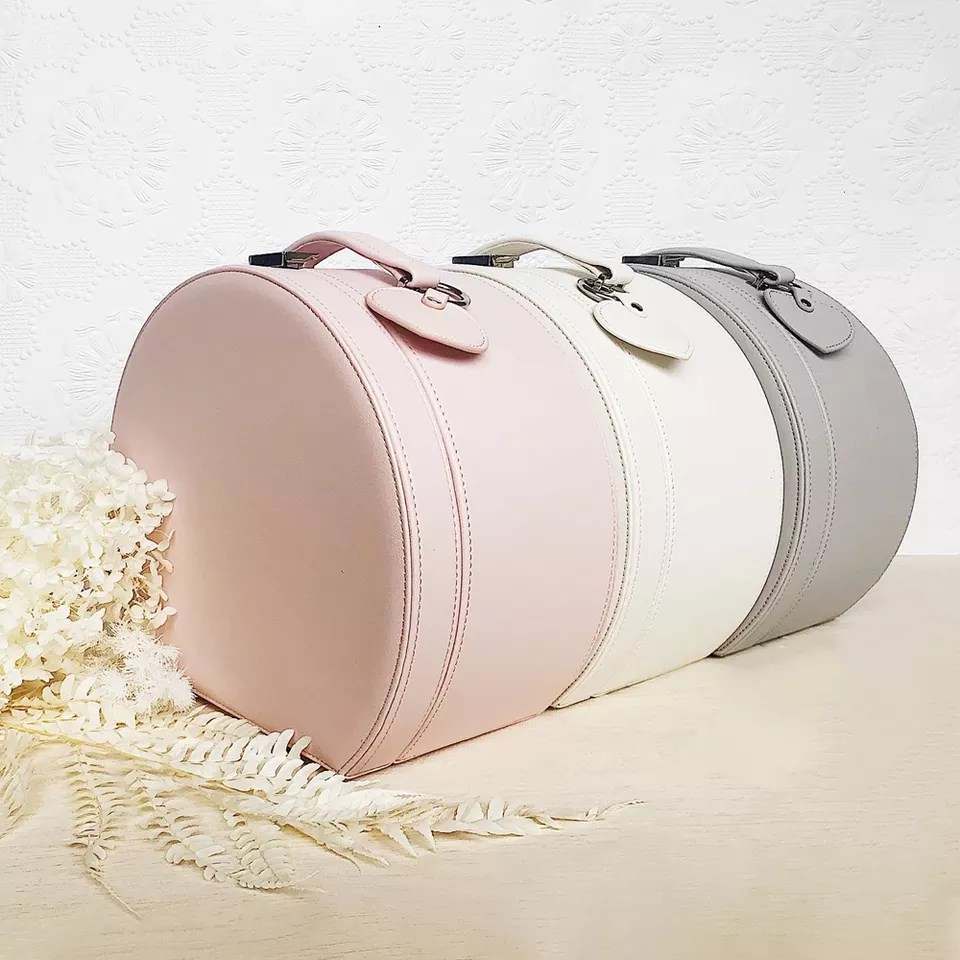 Blush pink and cream round keepsake boxes with gold-tone clasps and handles