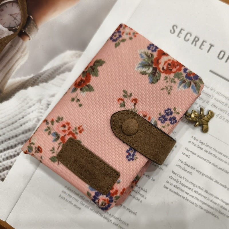Tri-fold wallet with pink floral print, two front card pockets and snap clasp