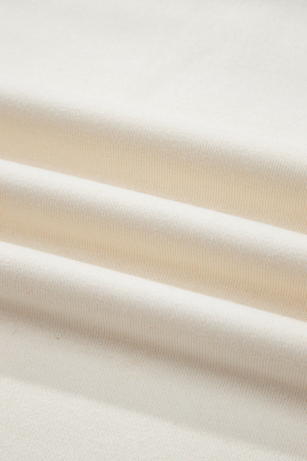 Cream knit sweatshirt fabric close-up with subtle ribbed texture
