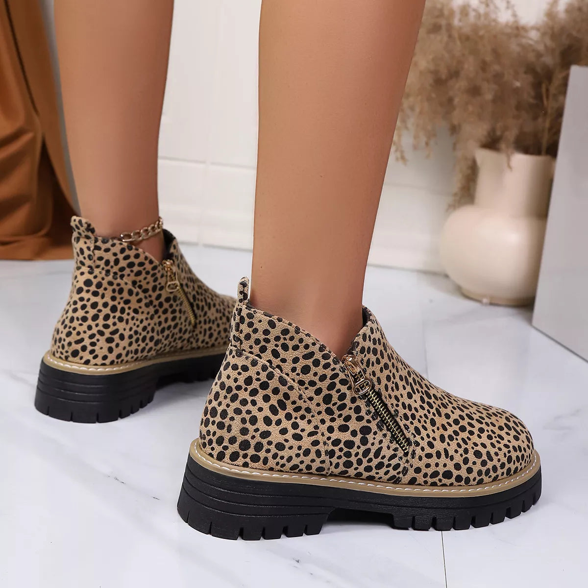 Leopard print ankle boots with side zipper and black lug sole, close side view