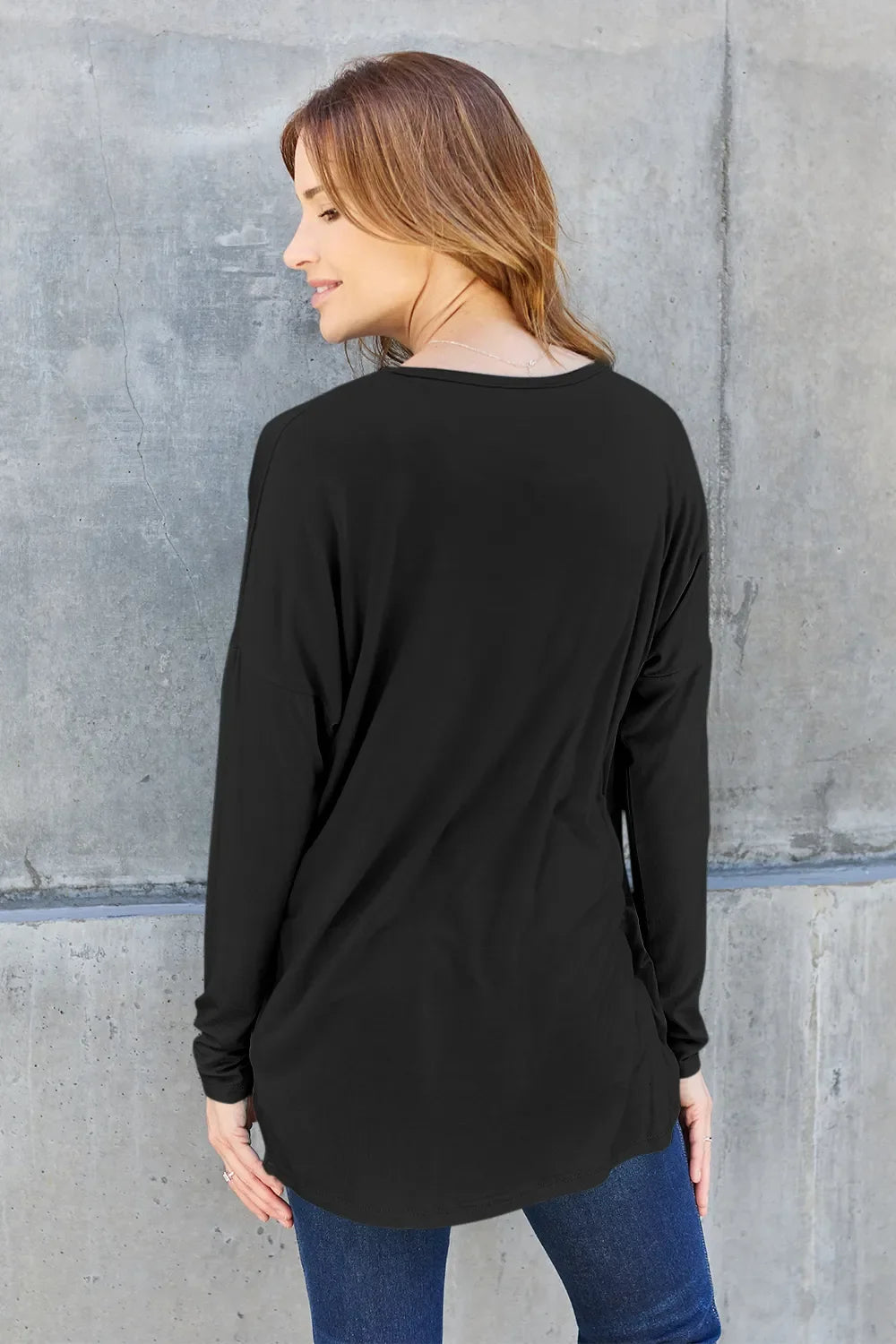 Black relaxed long sleeve crewneck tee, back view with curved hem