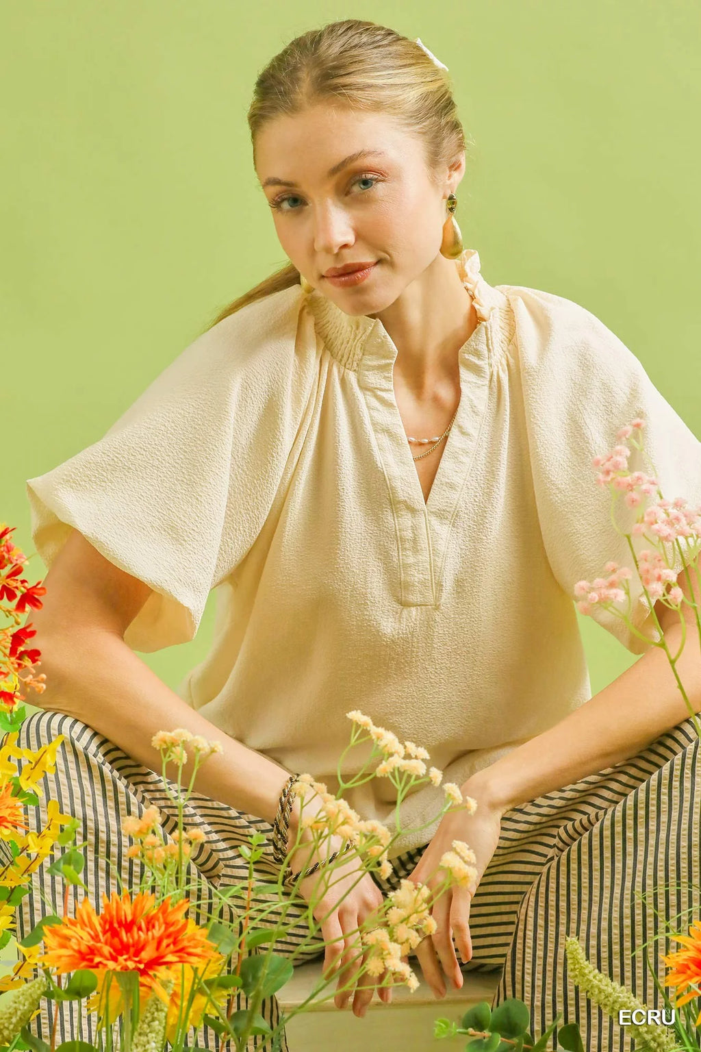 Ecru textured blouse with short puff sleeves, V-neck, and scalloped hem detail