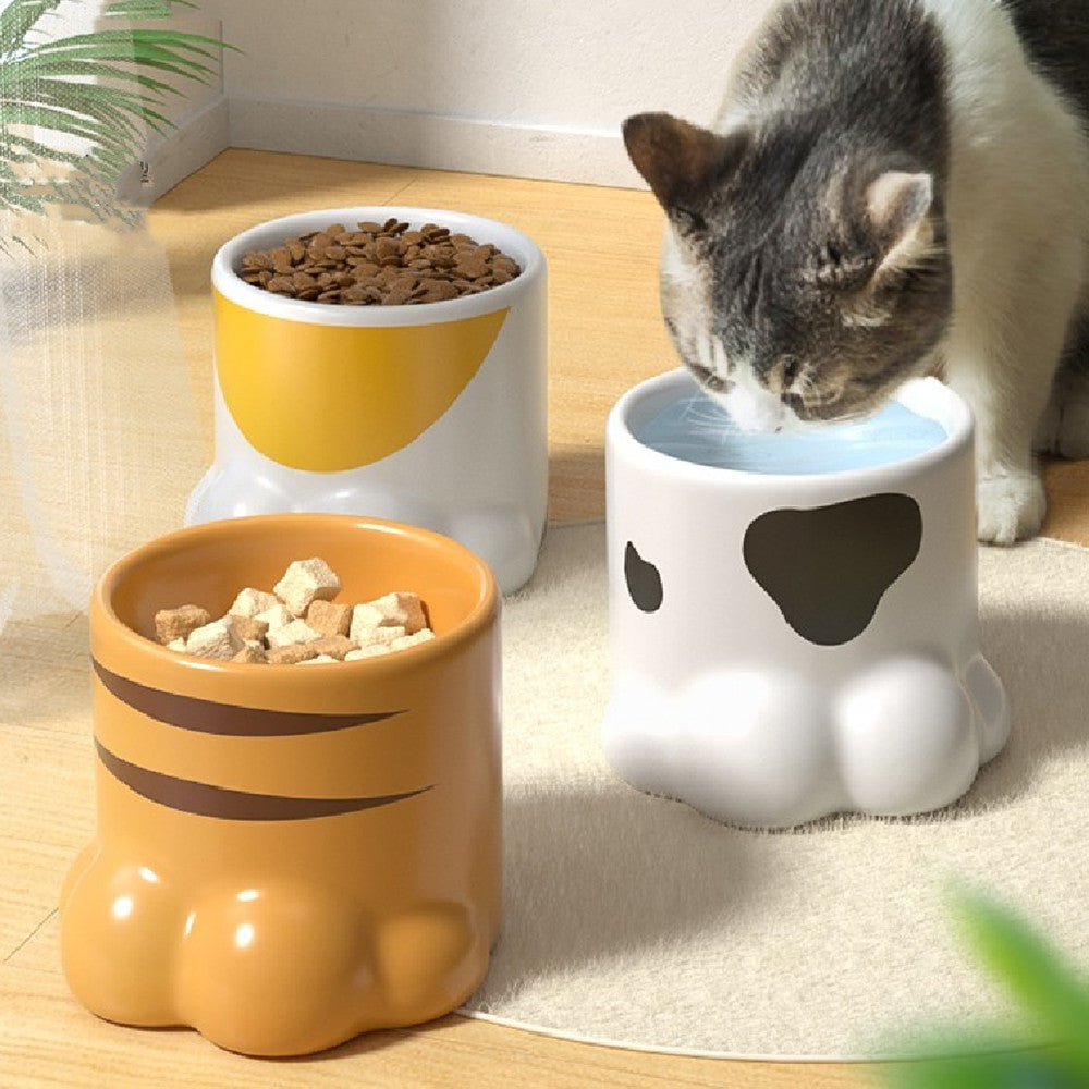 Ceramic cat bowl set with white paw design and orange stripes, filled with dry food