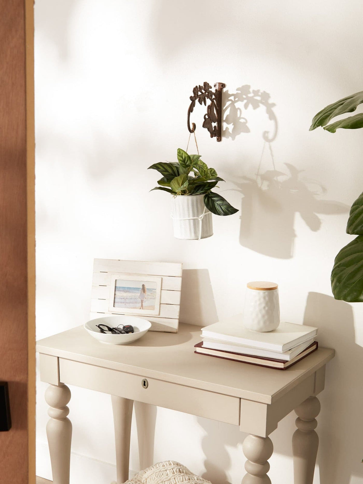 Wall-mounted cast iron planter bracket with butterfly design holding a small pot