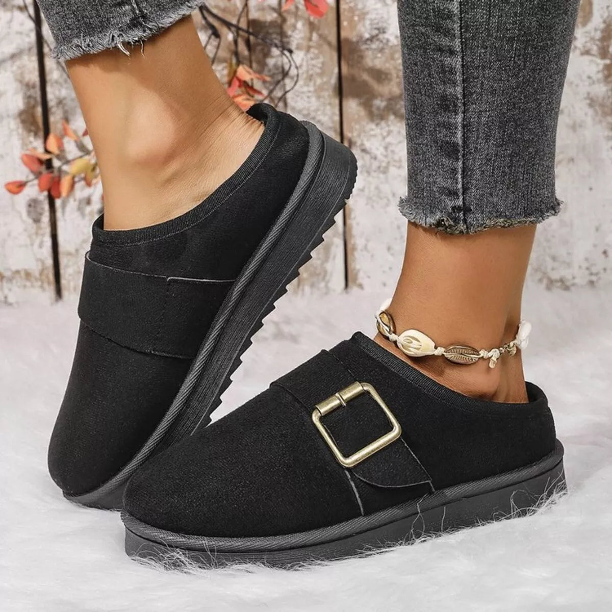 Black plush-lined slip-on slippers with square buckle detail and low-profile sole