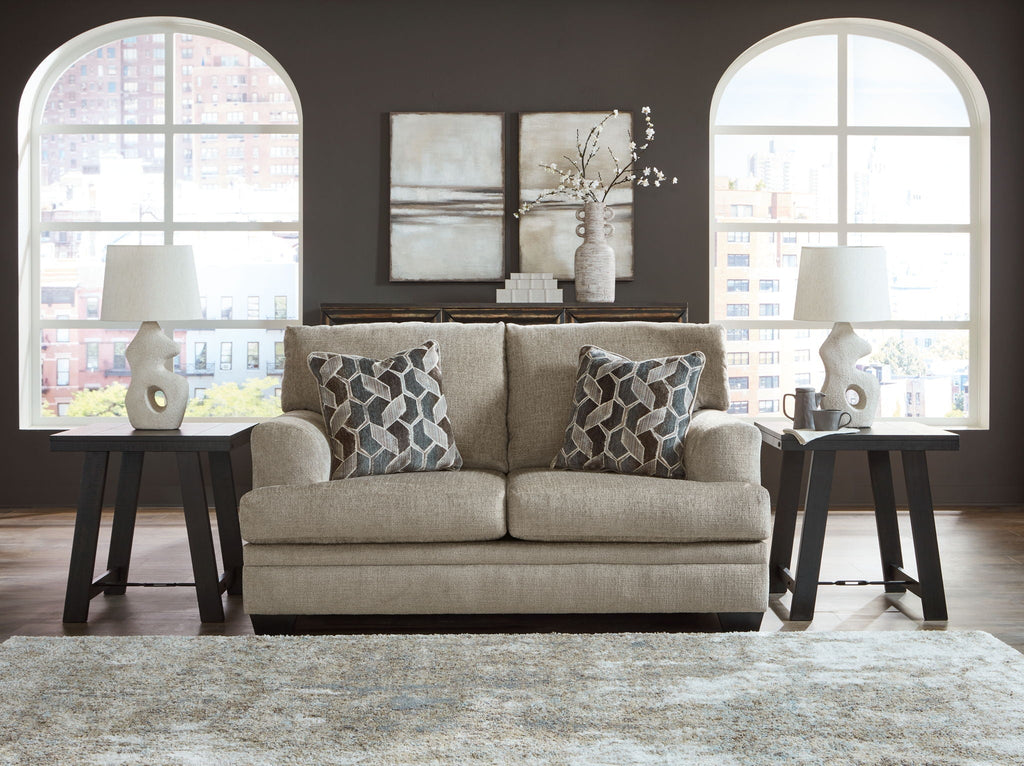 Upholstered loveseat in light gray fabric with two geometric accent pillows and dark legs