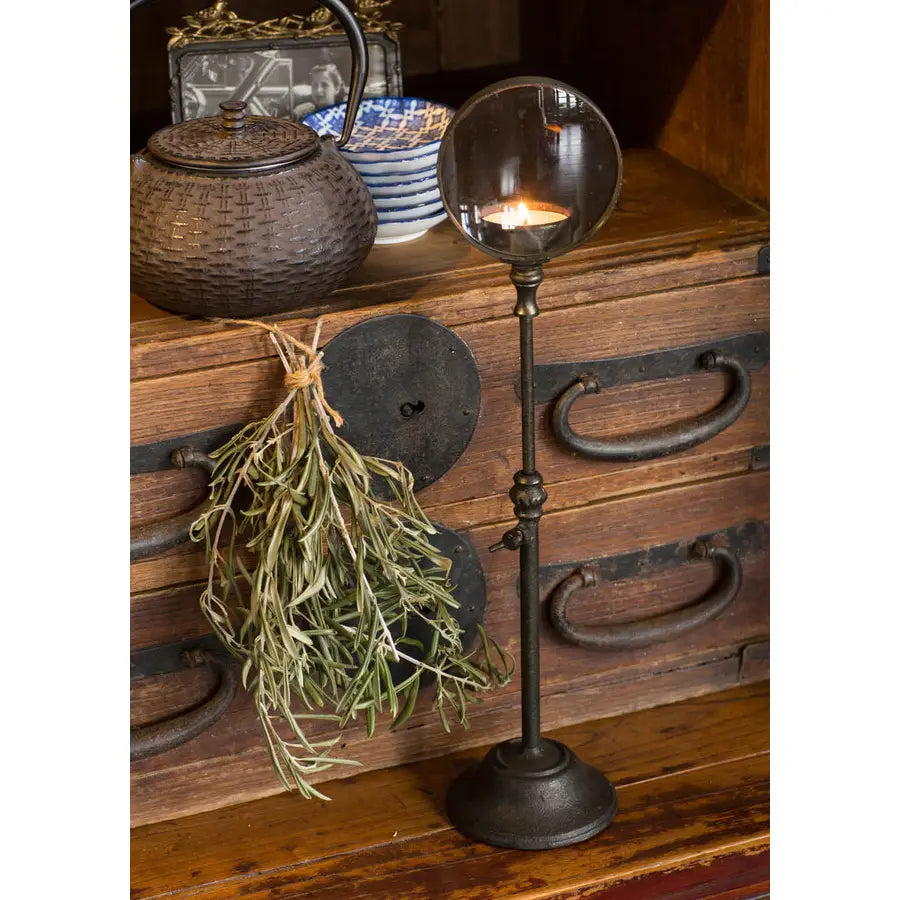 Iron candle holder with magnifying glass globe and flame, tall stem on round base