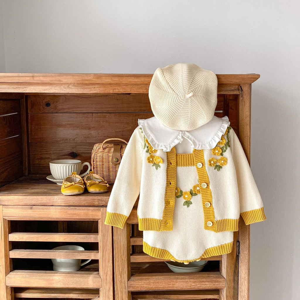 Cream baby coat with mustard panels, flower appliques, ruffled neckline, knit cuffs