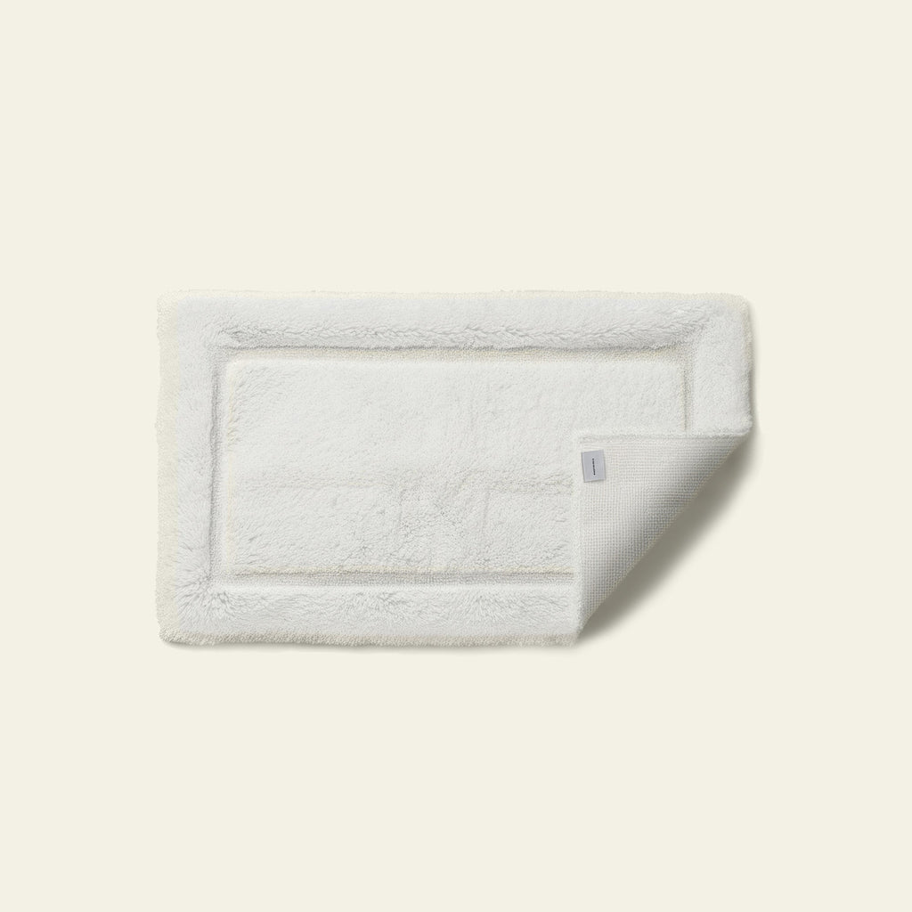 White rectangular bath mat with stitched border detail