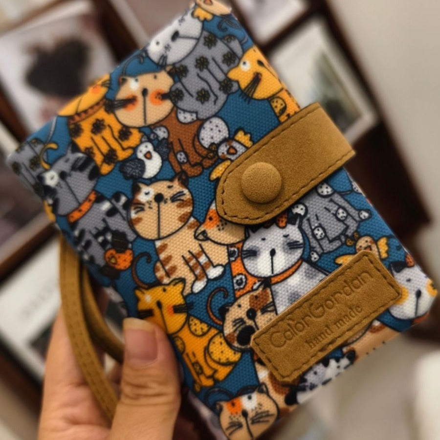 Printed tri-fold wallet with snap button, blue dog and cat pattern, tan leather label