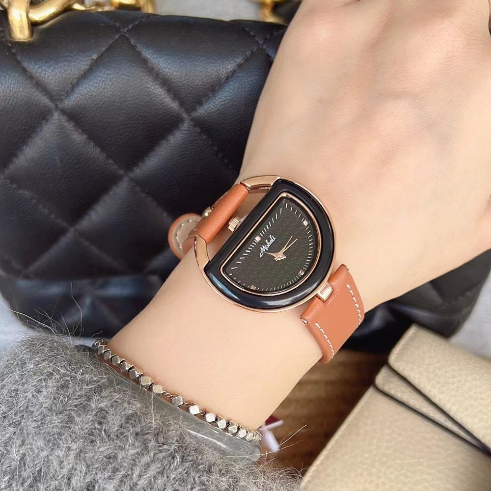 Women’s leather-strap watch with tan band and gold-toned oval case, dark dial.
