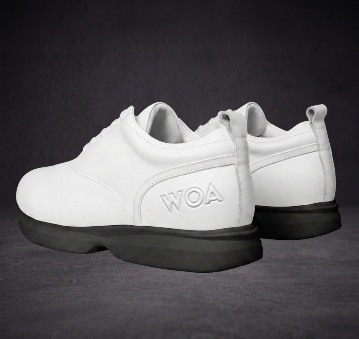White WOA sneakers with lace-up design, side logo, and black soles