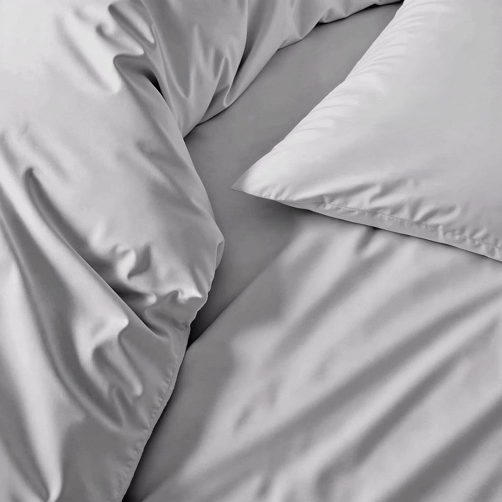 Light gray sateen duvet cover close-up showing glossy fabric folds and seam line