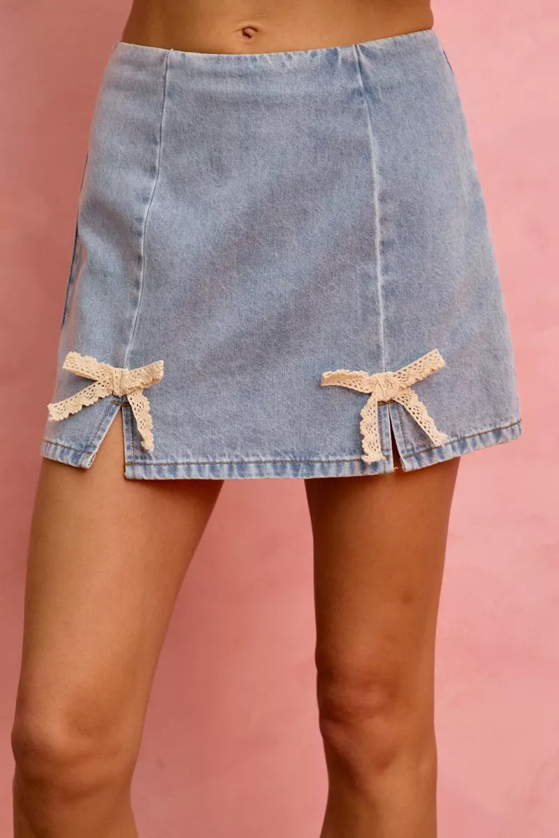 Light-wash denim mini skirt with two lace ribbon bow ties on hem
