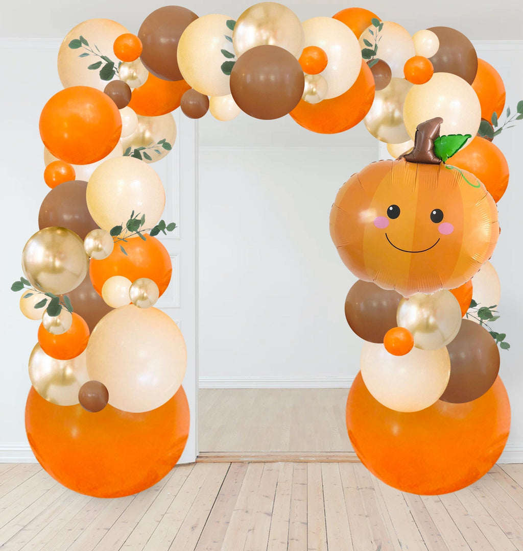 Woodland fall balloon garland kit with tall orange balloon arch and smiling pumpkin balloon
