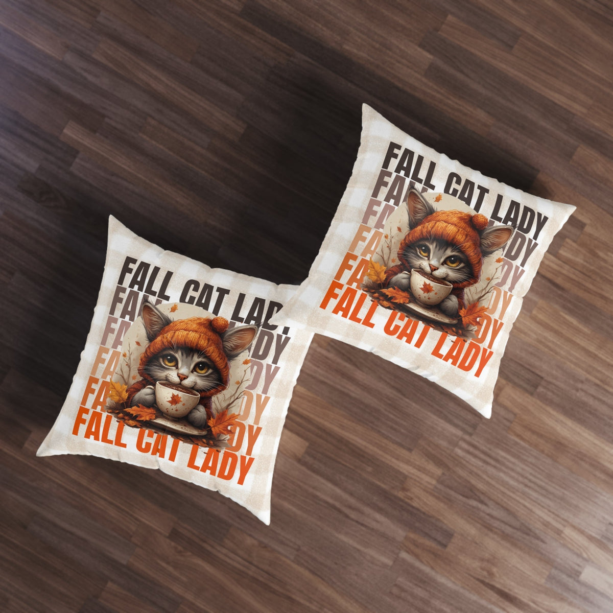 Pair of tufted floor pillows on wood floor, orange cat cup design, repeating 'FALL' text