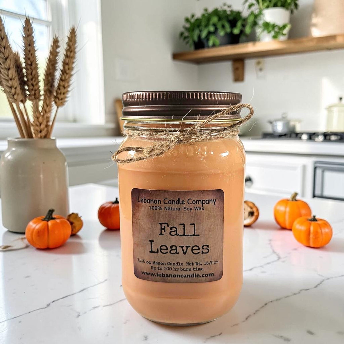 Amber jar candle with dark ribbed lid and twine ties, “Fall Leaves” label on front