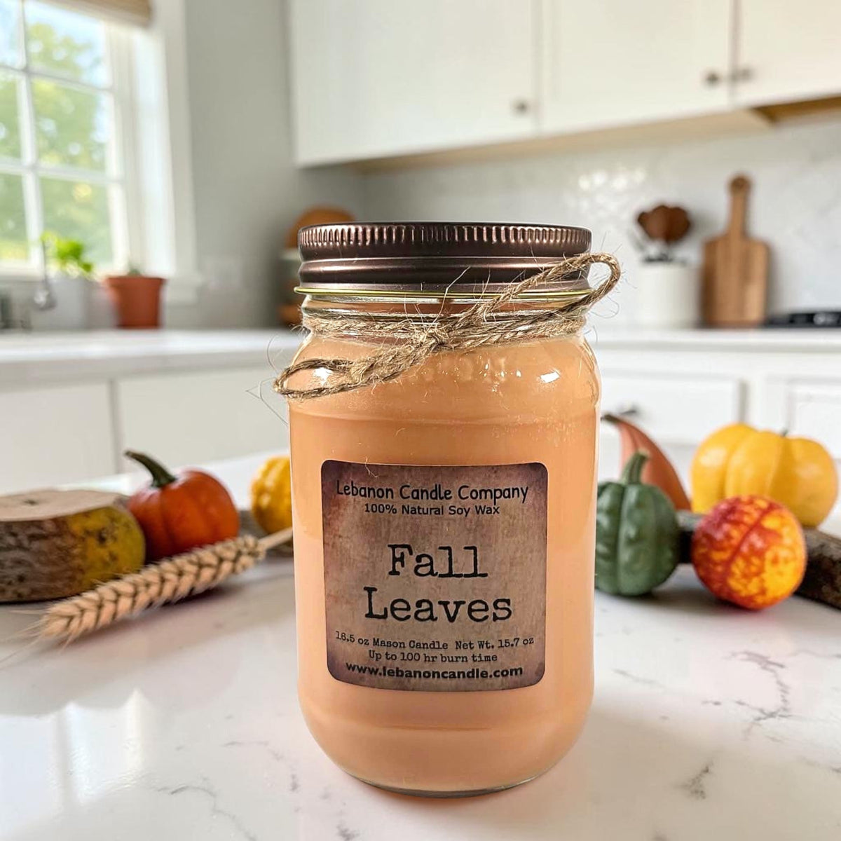 Amber jar candle with dark lid and twine, “Fall Leaves” label on jar front