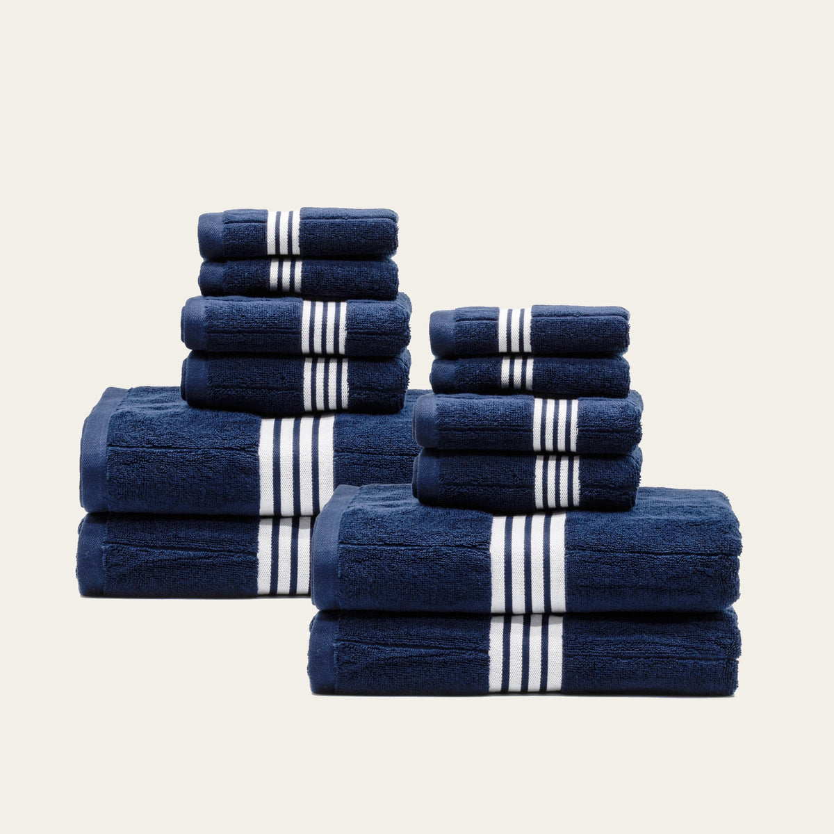 Assorted folded navy cotton towels with white striped bands, shown as multiple pieces