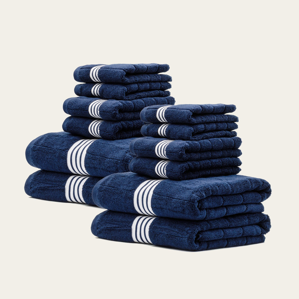 Multiple stacked navy towels with white striped bands, shown as a set